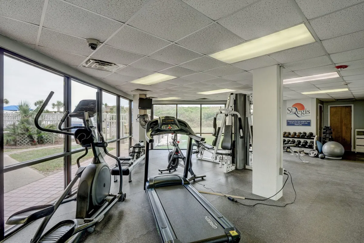 A bright fitness center outfitted with treadmills, elliptical machines, weight machines, and large windows providing natural light. The space feels motivating and modern—ideal for maintaining wellness routines.