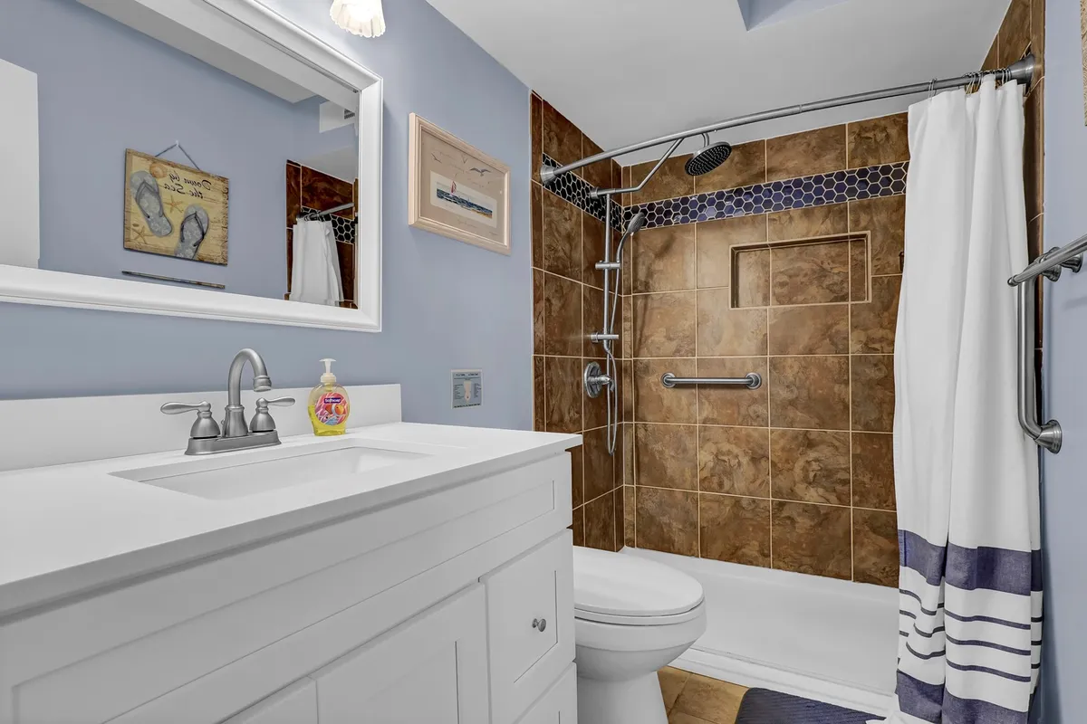 A modern bathroom with a vanity and sink, glass-enclosed shower, and decorative wall art. The space is clean, bright, and contemporary, exuding a sense of freshness and comfort.