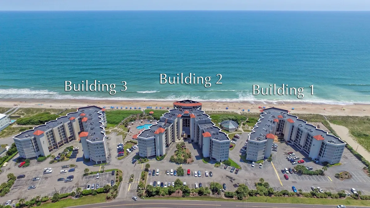 An expansive exterior view highlighting three distinct beachfront buildings, a sparkling swimming pool, and immediate beach access. The area is designed for family fun, with ample outdoor space for swimming, playing, and relaxing together by the water.